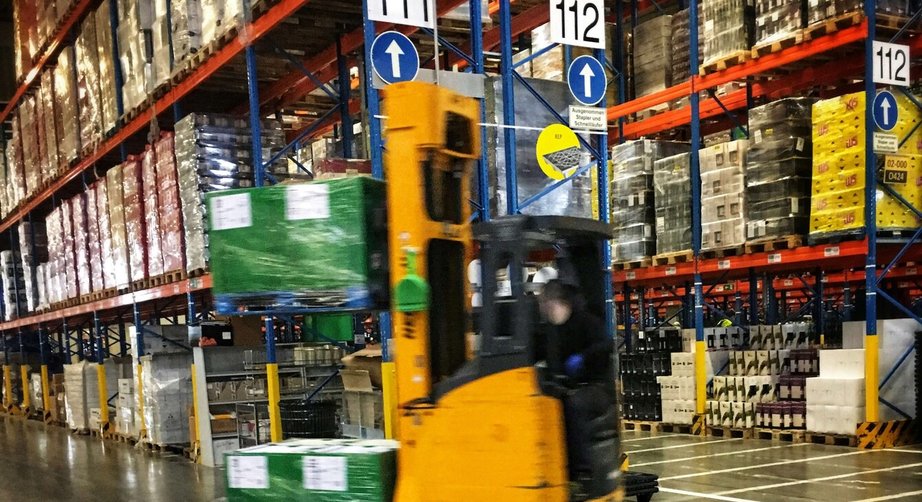 Entrepôt logistique avec en premier plan un chariot de manutention déplaçant des marchandises