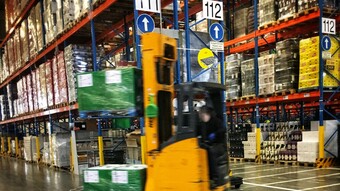 Entrepôt logistique avec en premier plan un chariot de manutention déplaçant des marchandises