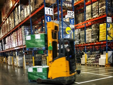 Entrepôt logistique avec en premier plan un chariot de manutention déplaçant des marchandises